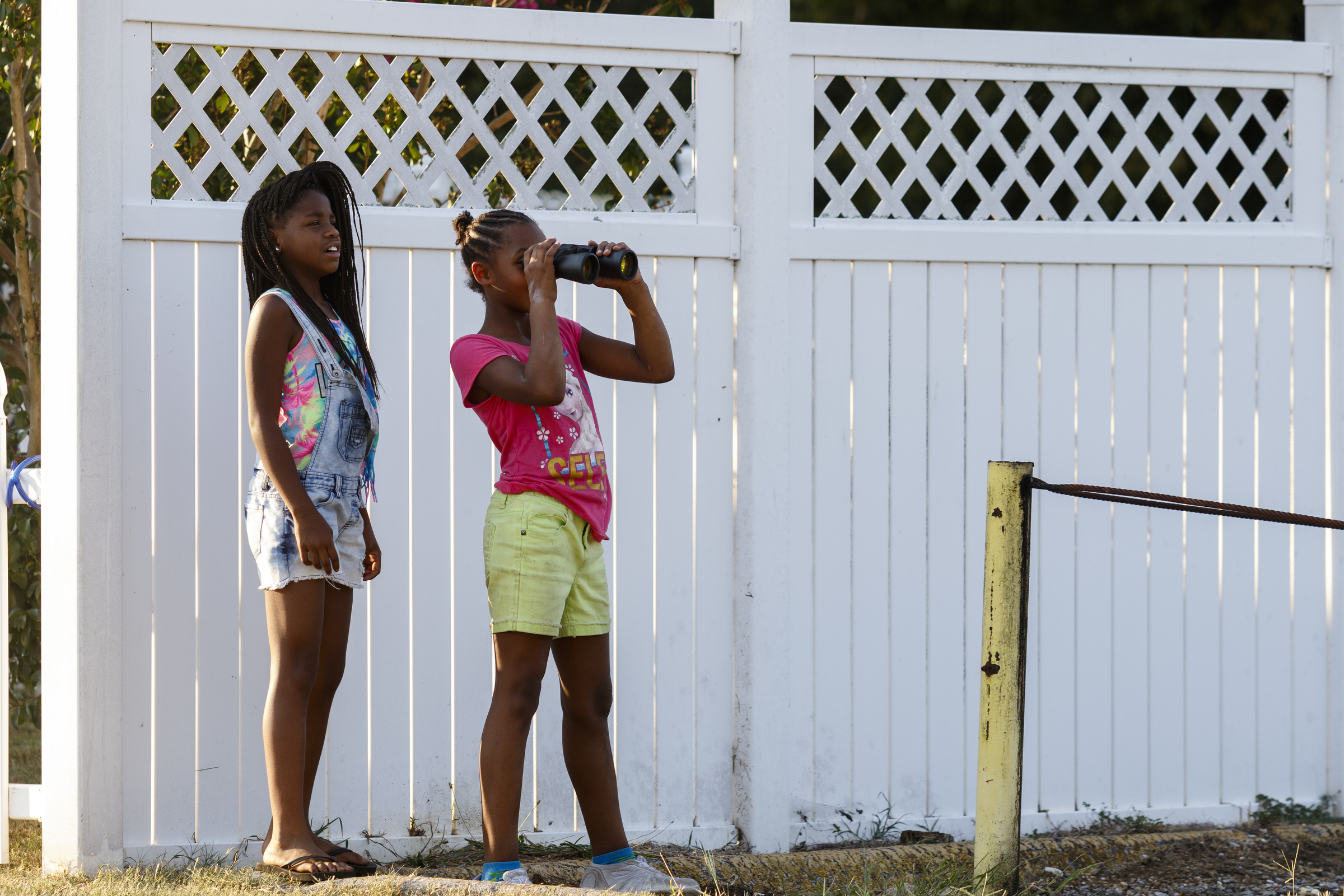 Jayda High, left, watches as Raegan Paris looks at the stage in the closed venue with binoculars from a nearby neighborhood home before a performance by artist Usher at Dalewood Middle School, his former school, on Friday, Sept. 9, 2016, in Chattanooga, Tenn. The concert concluded a string of activities and benefits by the artist in his home town.