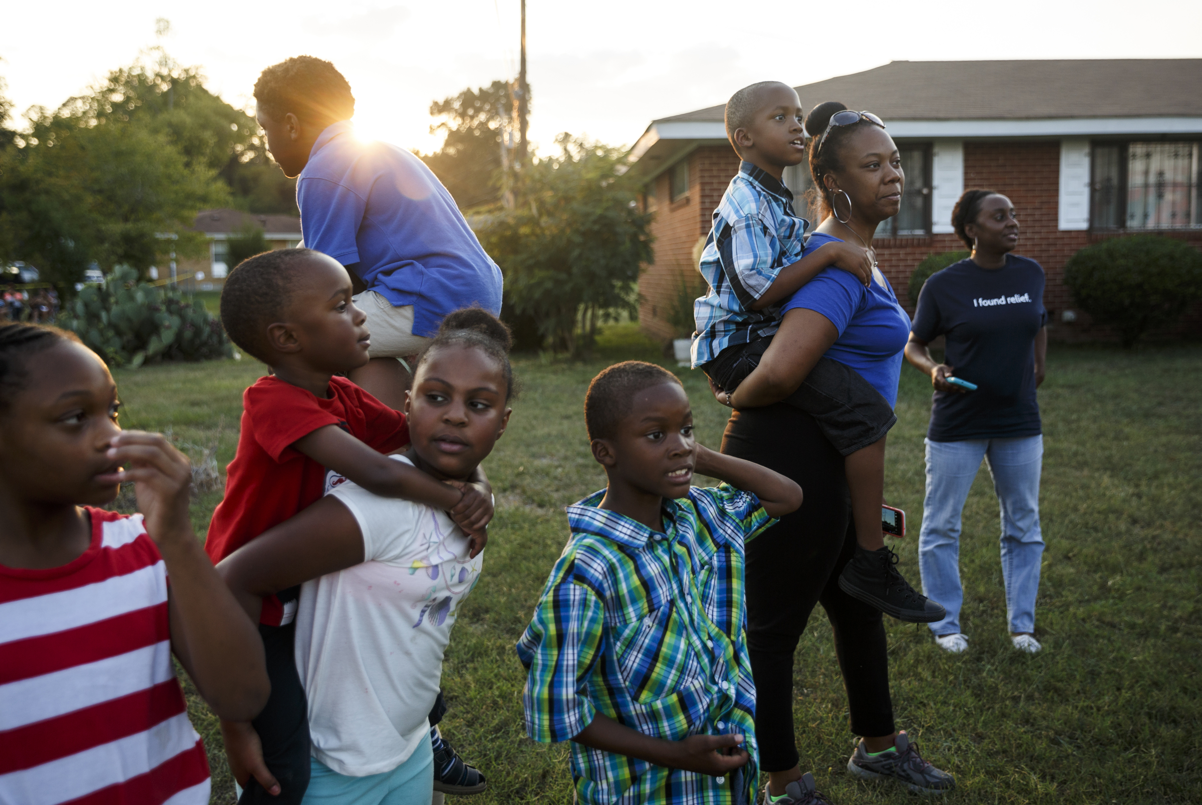 Neighborhood residents try to see over the fence surrounding the nearby closed venue before a performance by artist Usher at Dalewood Middle School, his former school, on Friday, Sept. 9, 2016, in Chattanooga, Tenn. The concert concluded a string of activities and benefits by the artist in his home town.