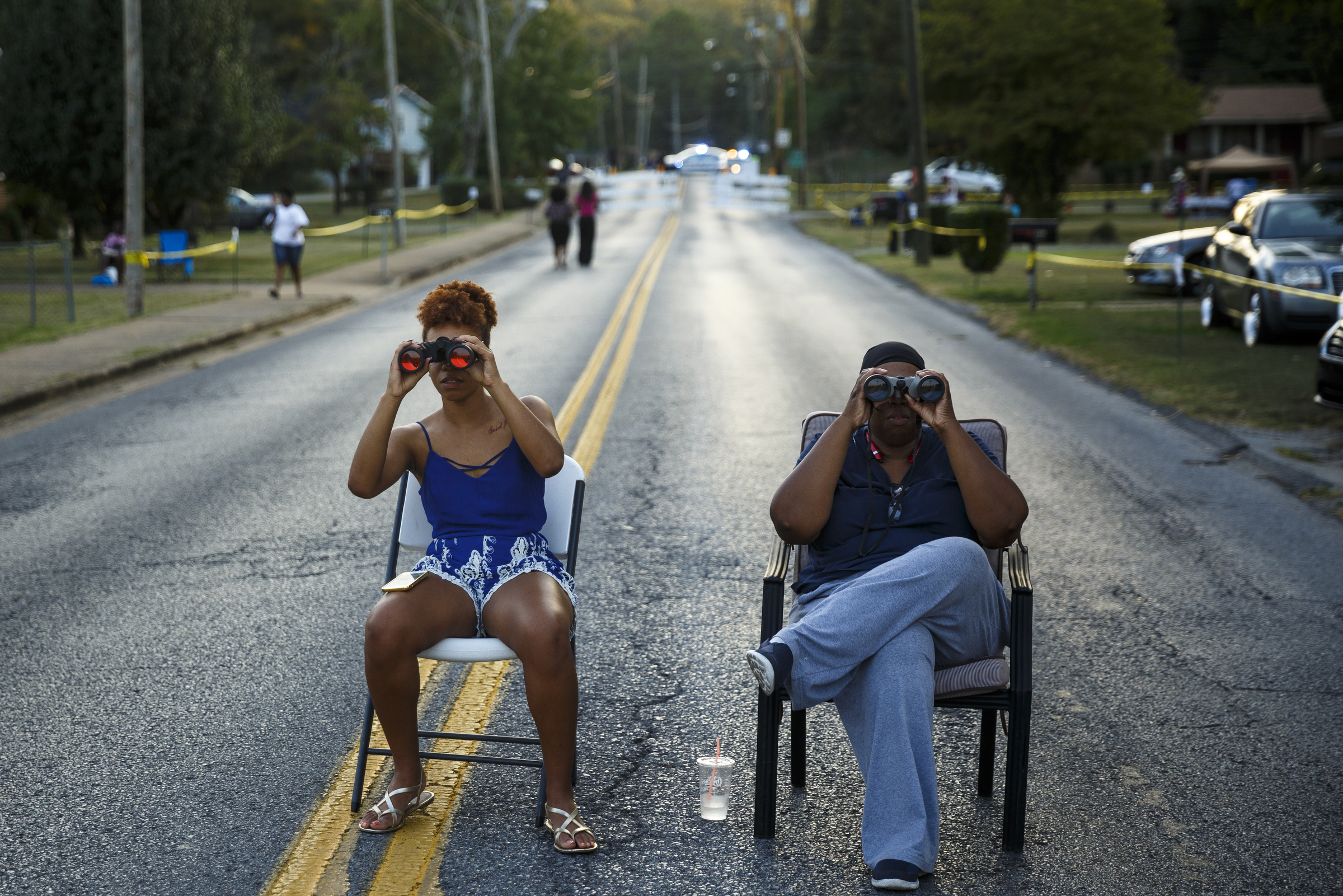 Gabrielle Mott, left, and LaShaunda Hammonds use binoculars to look into the closed venue from their seats in Shallowford Road before a performance by artist Usher at Dalewood Middle School, his former school, on Friday, Sept. 9, 2016, in Chattanooga, Tenn. The concert concluded a string of activities and benefits by the artist in his home town.
