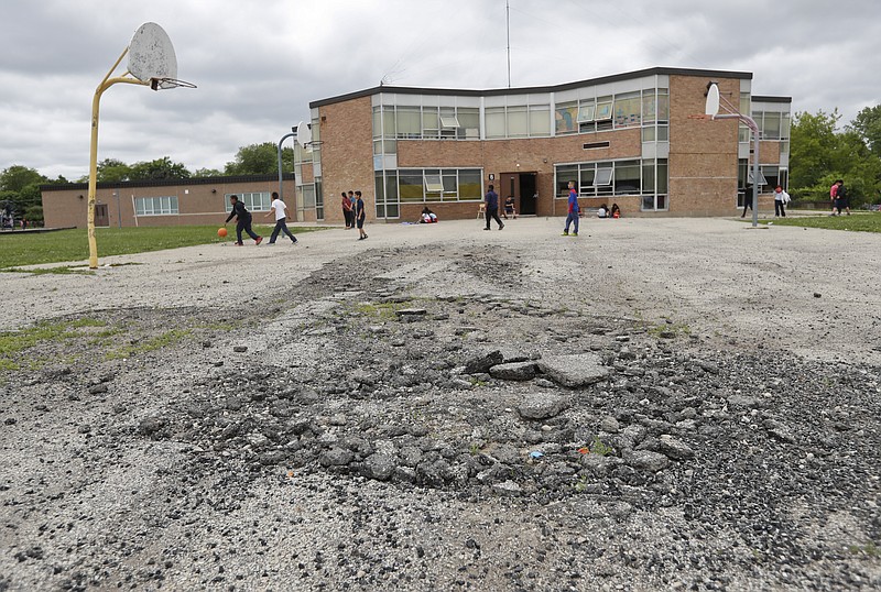 In this Tuesday, June 7, 2016 photo, students play basketball outside at Little Fort Elementary school in Waukegan, Ill. In the years following the 2008 financial crisis, school districts serving poor communities generally have been hit harder than more affluent districts, according to an Associated Press analysis of local, state and federal education spending. (AP Photo/Kamil Krzaczynski)