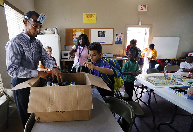 
              Miguel Moll, left, hands out snacks to children arriving to an after school program at an apartment complex, Friday, Sept. 2, 2016, in Fort Worth, Texas. Moll knew the risk of rape when he was thrown into a Texas jail in 1989 after joyriding in a stolen car. A generation later, the federal government has adopted guidelines intended to prevent prison rape in part by separating young offenders from adult inmates. (AP Photo/Tony Gutierrez)
            