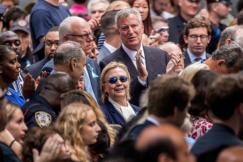 Prior to collapsing later as she entered a car, a wilted-looking Hillary Clinton, center, attends a ceremony at the Sept. 11 memorial in New York City on Sunday.