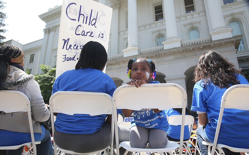 In this May 6, 2015, file photo Saryah Mitchell, sits with her mother, Teisa, Gay, left, a rally calling for increased child care subsidies at the Capitol in Sacramento, Calif. In much of the U.S., families spend more on child care for two kids than on housing. And if you're a woman, it's likely you earn less than your male colleagues even though one in four households with kids relies on mom as the sole or primary breadwinner. 