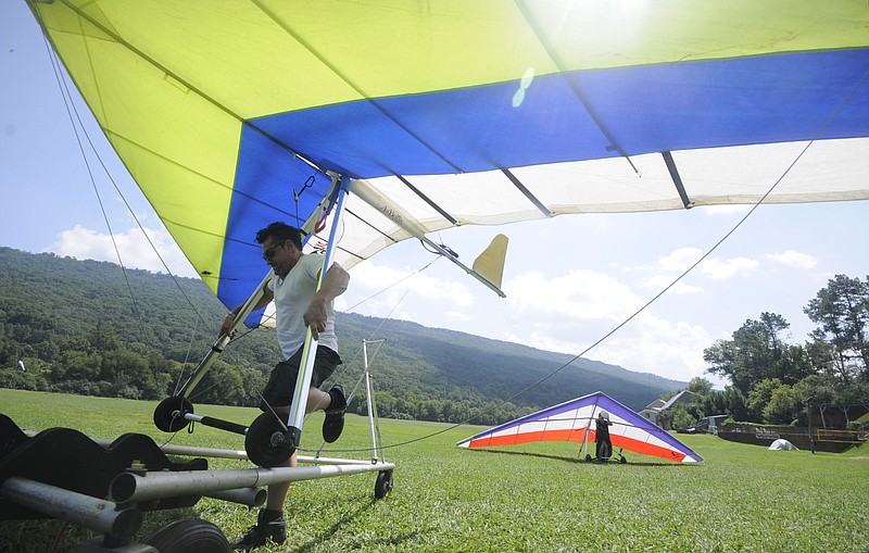 Dana Daniels, a mobile disc jockey from Atlanta, moves his glider into position for transport after a 20- minute flight from the top of Lookout Mountain Flight Park. "I got about 1,000-feet above the mountain just after take-off," Daniels said. Jen Richards, back, and employee in the pro-shop atop Lookout Mountain, walks her glider to the break-down area after landing. 