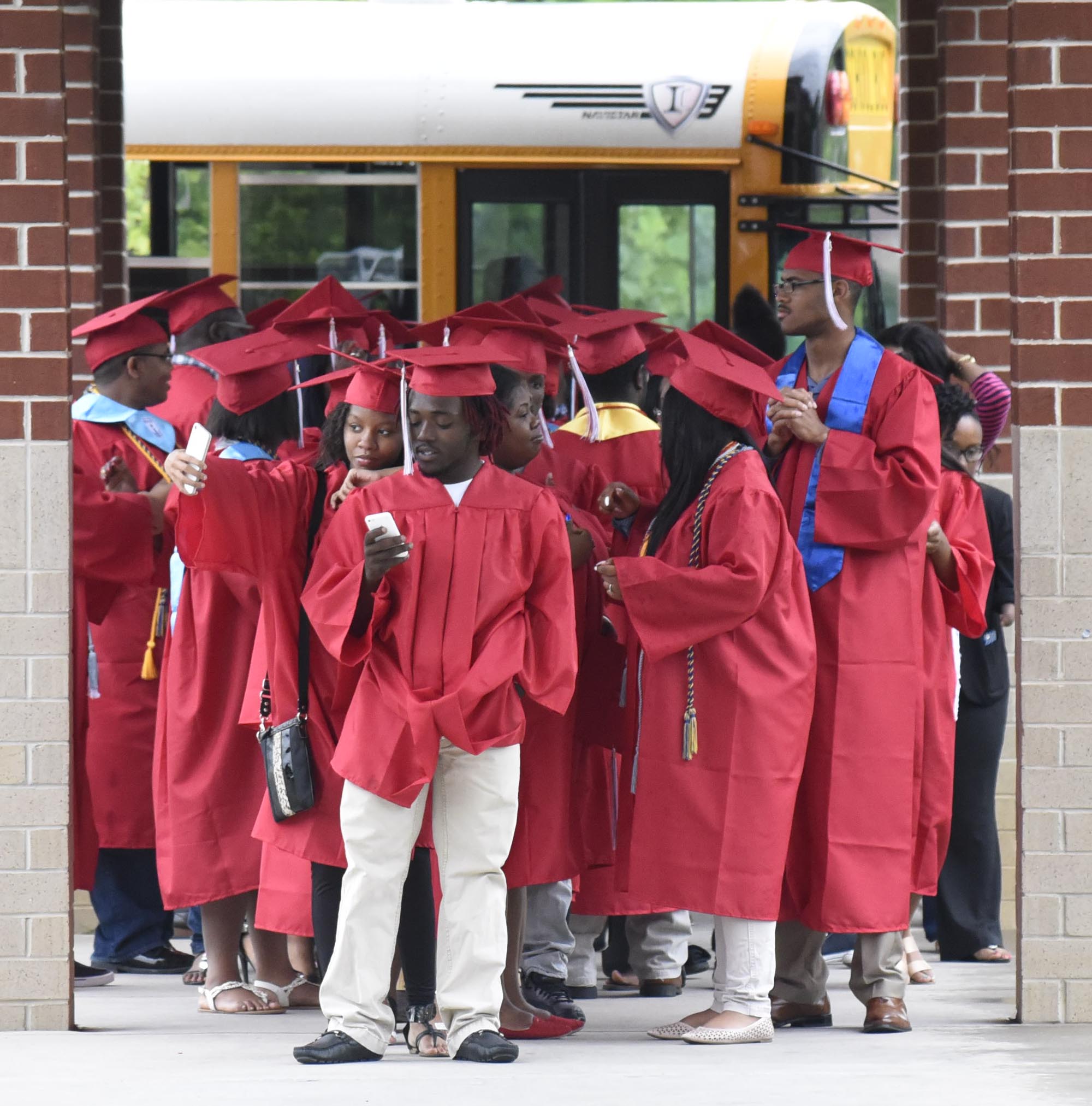 Brainerd seniors check their phones and take selfies as they prepare to process into Orchard Knob Elementary. The 2016 graduating class of Brainerd High School walked through the halls of Orchard Knob Elementary in their caps and gowns, as a representation of the "vision" for where the elementary students will one day be.