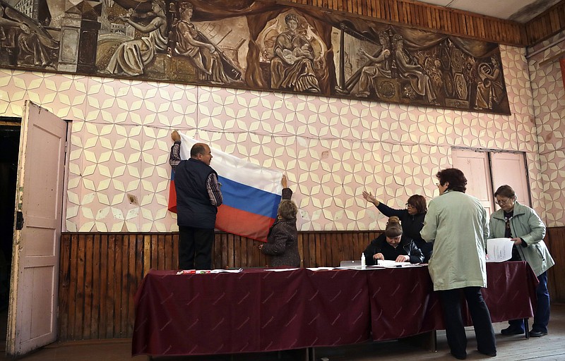 
              Election officials place a Russian state flag at a polling station ahead of Sunday's parliamentary elections in the village of Gusino, outside Smolensk, western Russia, Saturday, Sept. 17, 2016. Russia's weekend parliament elections take place under new rules that in principle could bring genuine opposition into the national legislature. But the Kremlin-backed United Russia and the parties that almost always follow its lead are set remain the overwhelming presence in the State Duma. (AP Photo/Sergei Grits)
            