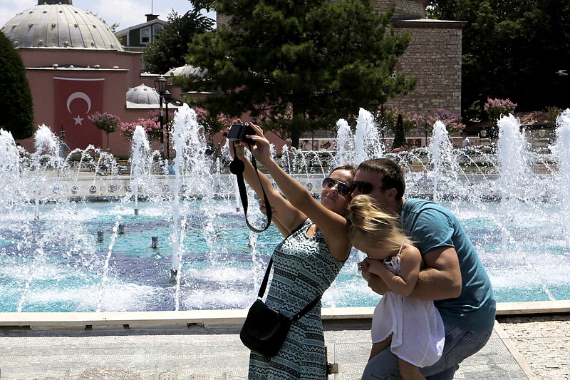 
              FILE - In this Tuesday, July 26, 2016 file photo,  tourists take a selfie at the Byzantine-era Hagia Sophia, in the historic Sultanahmet district of Istanbul. With summer drawing to a close, Turkey is counting the cost of a tough year that saw a string of terrorist bombings and a diplomatic spat with Moscow that cut deep into the country’s crucial tourist trade. (AP Photo/Petros Karadjias, File)
            