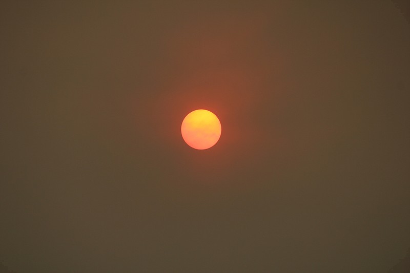 The morning sun is reduced to an orange disk in withering heat. (AP Photo/John Antczak)