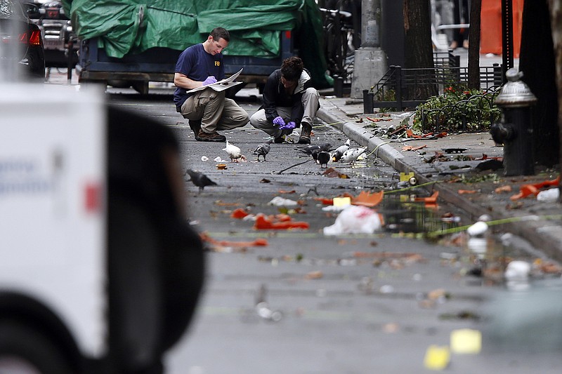 
              Evidence teams investigate at the scene of Saturday's explosion on West 23rd Street in Manhattan's Chelsea neighborhood, Monday, Sept. 19, 2016, in New York. Ahmad Khan Rahami, wanted in the bombings that rocked Chelsea and a New Jersey shore town was captured Monday after being wounded in a gun battle with police that erupted when he was discovered sleeping in a bar doorway, authorities said. (AP Photo/Jason DeCrow)
            