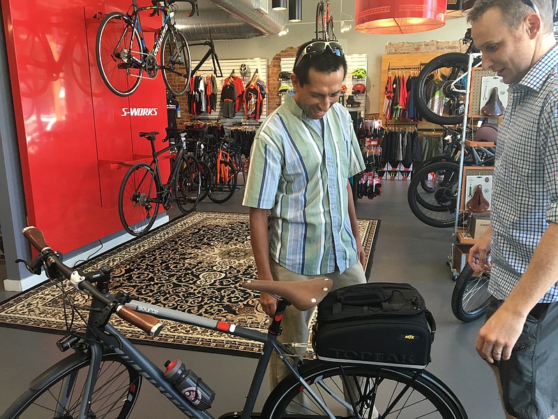 Nelson Barrios, left, checks out his new Specialized Source Eleven bicycle on Wednesday at Cycle Sport Concepts on Main Street. Barrios won the bike by logging the most bicycle commuting miles in the iBikeCha initiative this summer. Electric Bike Specialists owner Chandlee Caldwell, right, organized the initiative, which offered incentives to bicycle commuters.

