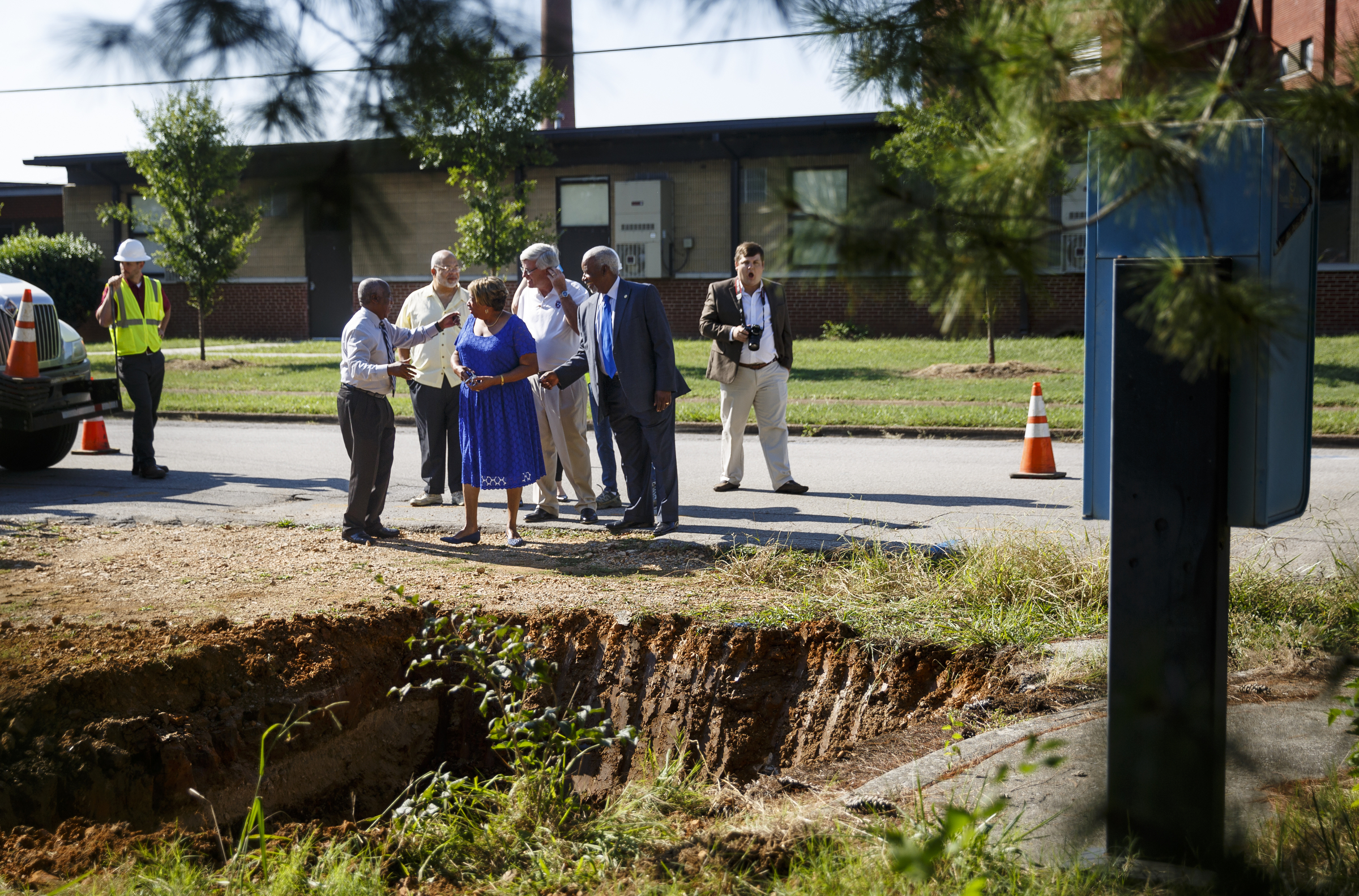 Officials arrive for a photo op near where an excavator is taking an old water main out of service so new construction can begin at the old site of Maurice Poss Homes near Howard School on Wednesday, Sept. 21, 2016, in Chattanooga, Tenn. Officials hope to use the site to build a new stadium for Howard.