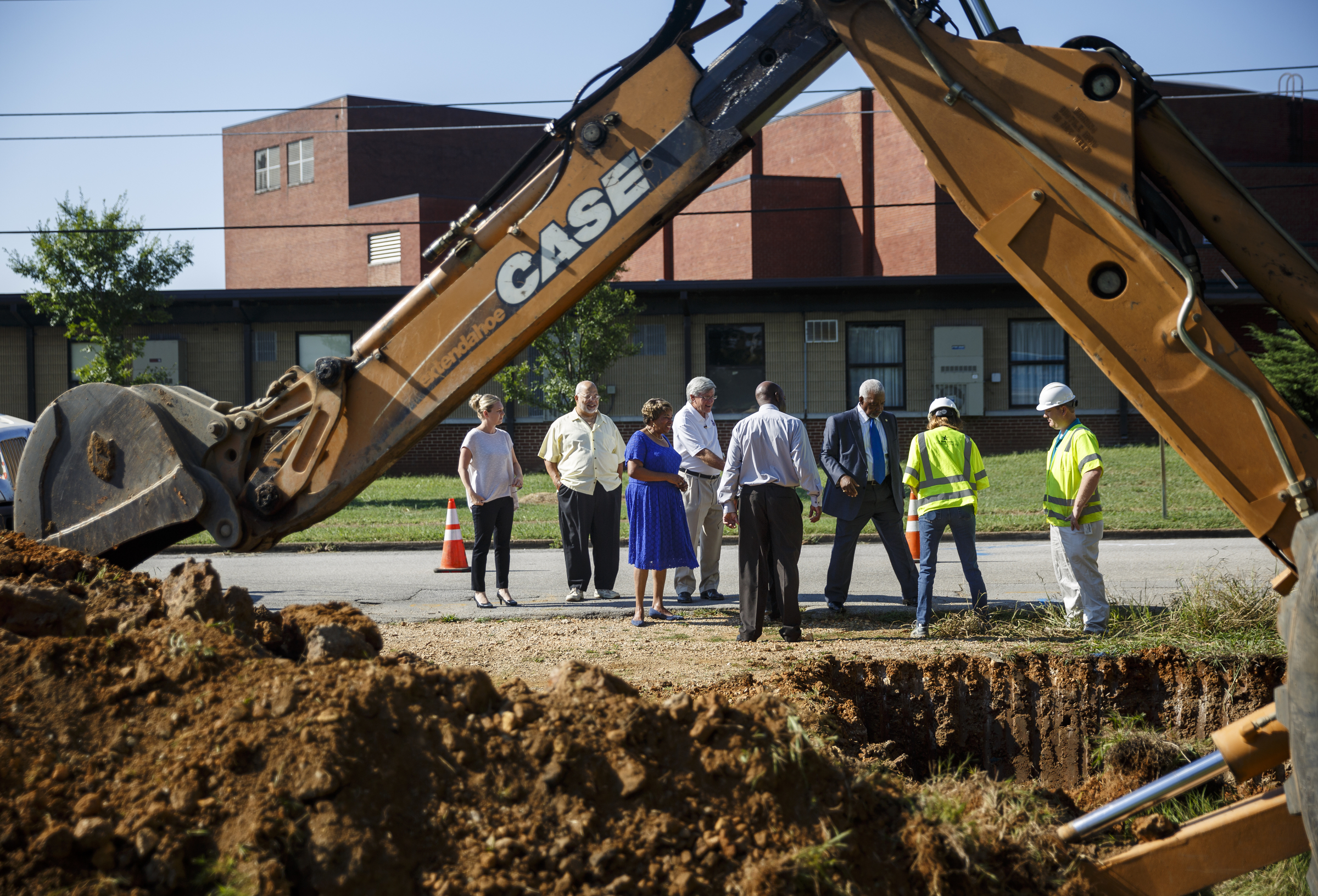 Officials arrive for a photo op near where an excavator is taking an old water main out of service so new construction can begin at the old site of Maurice Poss Homes near Howard School on Wednesday, Sept. 21, 2016, in Chattanooga, Tenn. Officials hope to use the site to build a new stadium for Howard.