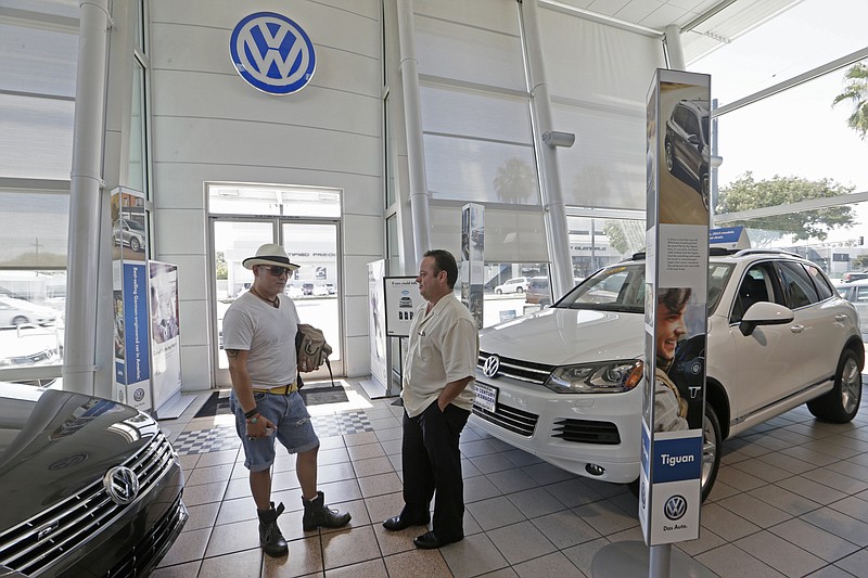 FILE - In this Thursday, July 2, 2015, file photo, customer Armando Barillas, originally from Guatemala, left, talks to Sergio Rosas, sales manager at the New Century Volkswagen dealership in Glendale, Calif. For bargain hunters willing to be patient, some car-buying times are better than others. Seasonal fluctuations and carmakers’ redesign schedules can often lead to good deals. (AP Photo/Damian Dovarganes, File)