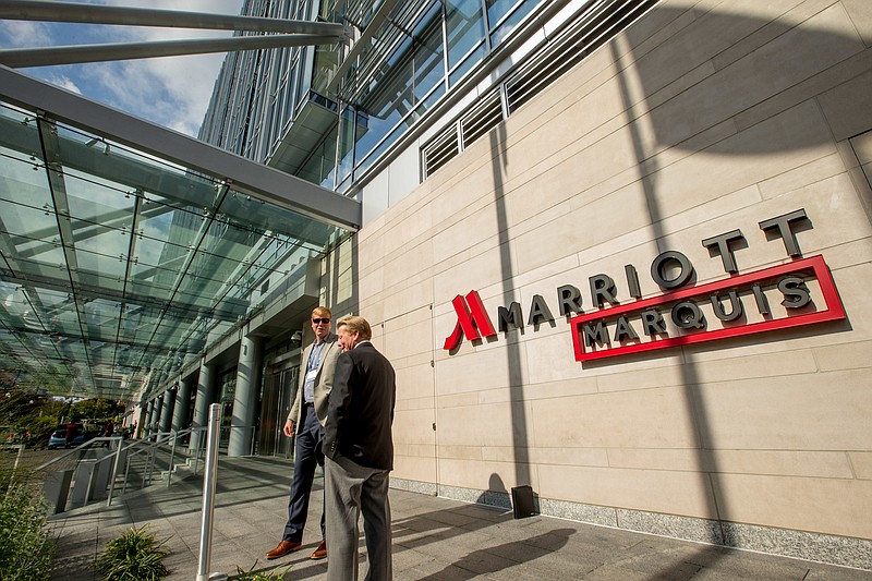 
              FILE - In this Wednesday, Oct. 14, 2015, file photo, two men stand outside the newly-built Marriott Marquis hotel in Washington. Marriott International closed early Friday, Sept. 23, 2016, on its acquisition of Starwood Hotels & Resorts Worldwide, bringing together its Marriott, Courtyard and Ritz-Carlton brands with Starwood’s Sheraton, Westin, W and St. Regis properties. (AP Photo/Andrew Harnik, File)
            