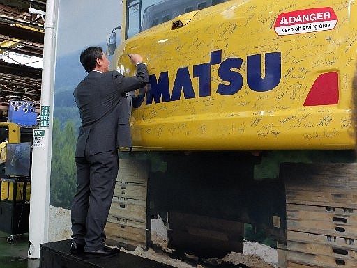 Komatsu America Corp. President and COO Max Moriyama signs the rear body of a piece of equipment during the 30th year celebration in Chattanooga.