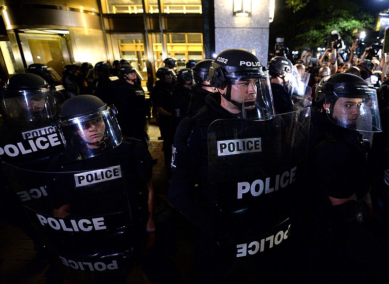 
              Police officers in riot gear stand by as protesters gather in Charlotte, N.C. on Thursday, Sept. 22, 2016.  The curfew has ended for Friday in Charlotte following a night of mostly peaceful protests of the shooting of Keith Lamont Scott by an officer. Charlotte Mayor Jennifer Roberts issued the curfew order Thursday night, to be in effect from midnight until 6 a.m. each day that the state of emergency continues. (Jeff Siner/The Charlotte Observer via AP)
            