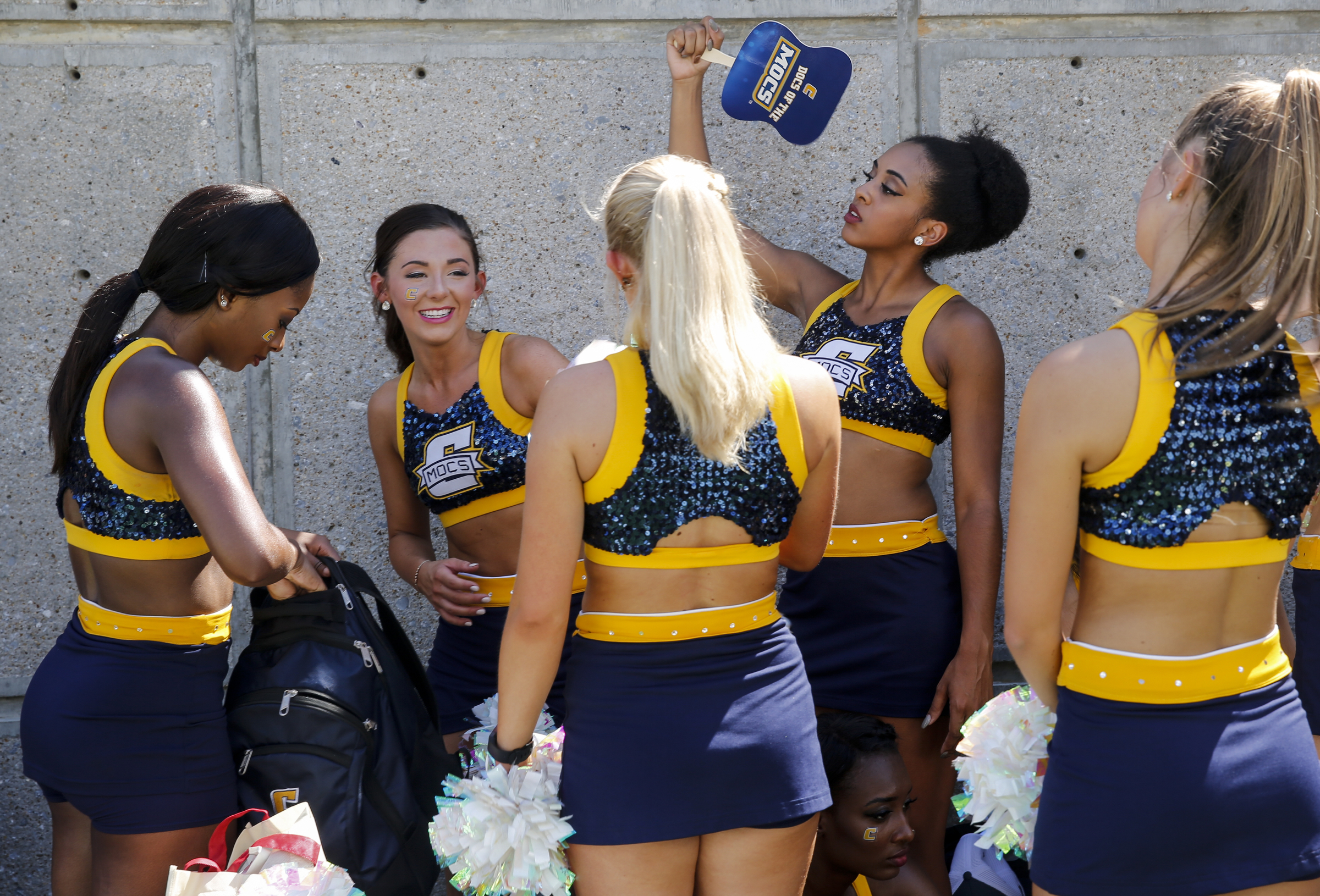 UTC cheerleaders fan themselves in the shade before the Mocs' home football game against the Samford Bulldogs at Finley Stadium on Saturday, Sept. 24, 2016, in Chattanooga, Tenn.