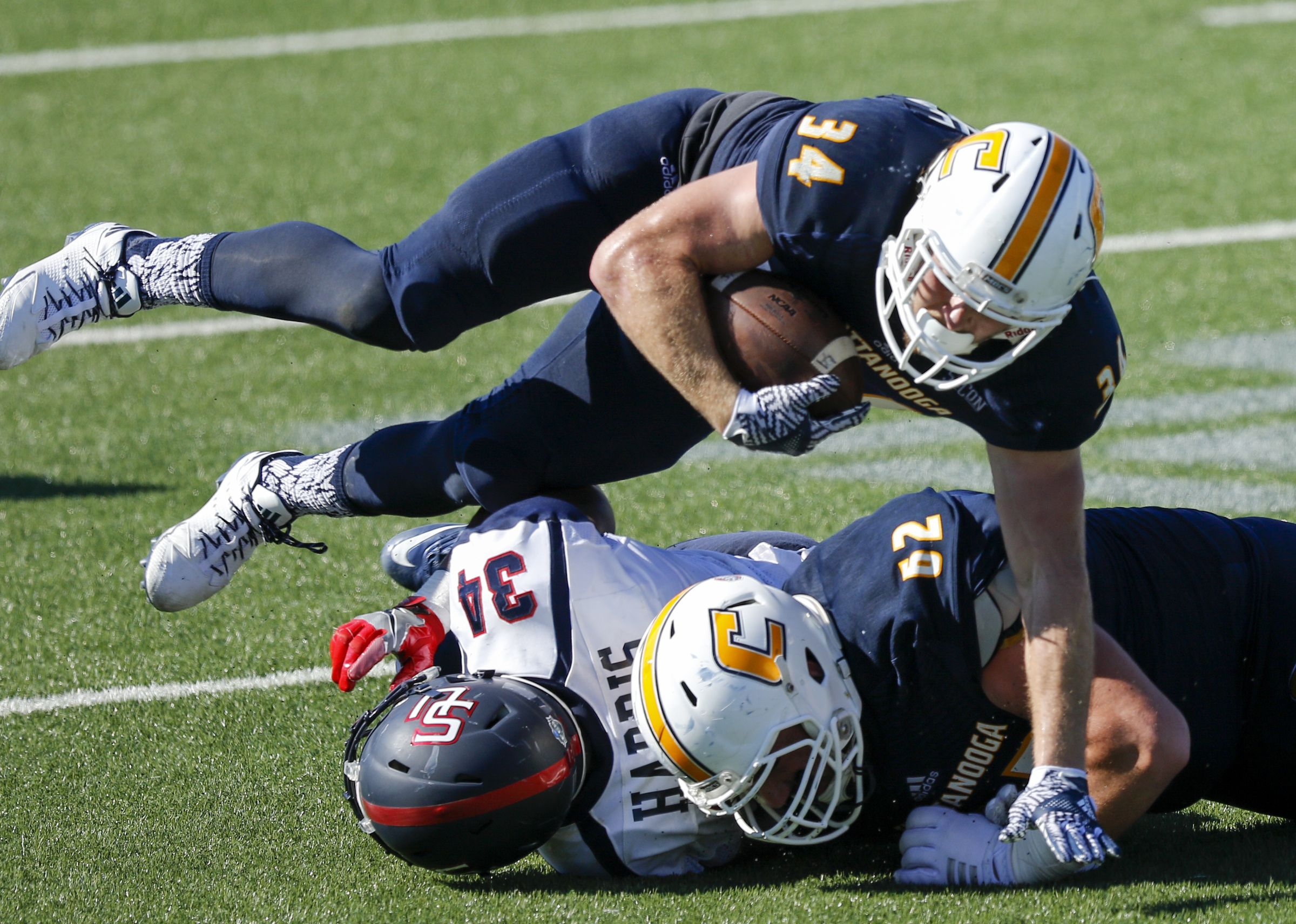 UTC running back Derrick Craine tumbles over teammate Jacob Revis (52) and Samford linebacker Aaron Harris during the Mocs' home football game against the Bulldogs at Finley Stadium on Saturday, Sept. 24, 2016, in Chattanooga, Tenn.