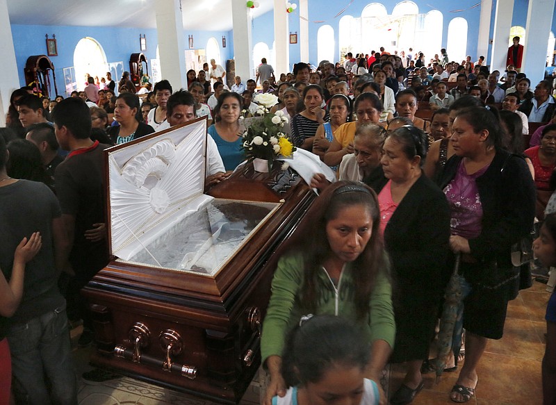 
              This Sept. 21, 2016 photo shows people paying their last respects to slain Rev. Jose Alfredo Suarez de la Cruz, who was found bound and shot to death alongside another priest, inside Our Lady of Asuncion Church in Paso Blanco, Veracruz state, Mexico, his hometown. In this eastern oil town already weary of rising gangland violence and extortion, the abduction and murder of two priests this week sank many residents only deeper into despair. (AP Photo/Marco Ugarte)
            