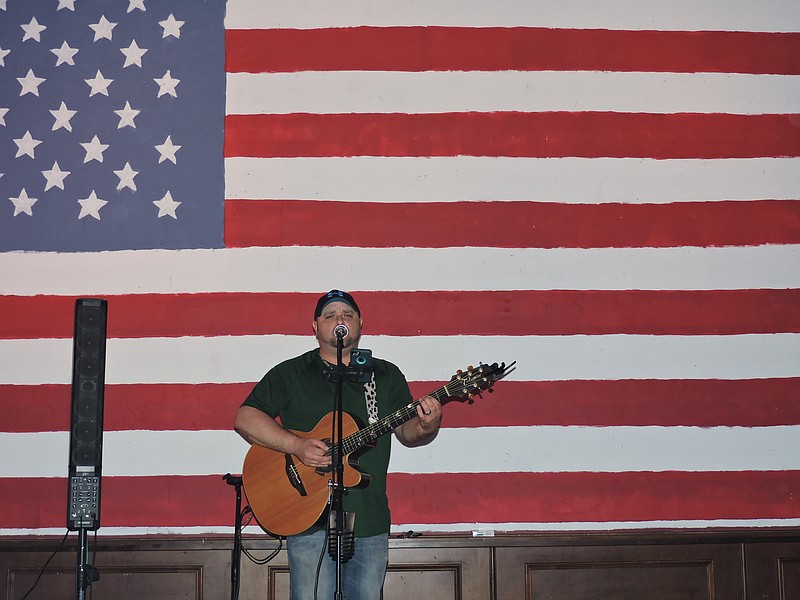 At Phibbs Bar and Grill, where the motto is "Eat, Drink Local," a handpainted American flag now serves as a patriotic backdrop. Pictured playing is Eric Garmany.