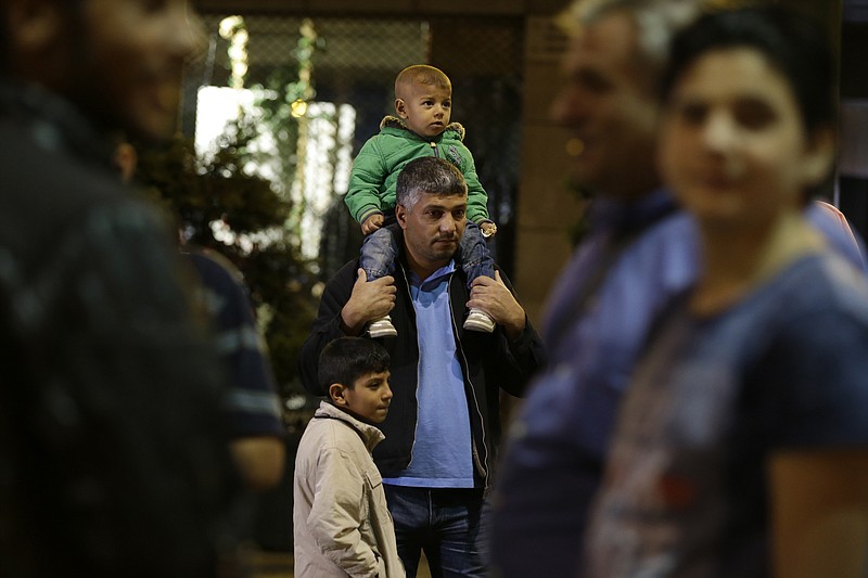 
              Syrian refugee Fadi Ehmood, center, waits with his children at Omonia square in Athens before heading to the airport for a flight to Madrid on Monday, Sept. 26, 2016. A group of 27 Syrians and four Iraqis was among the very few accepted by a European country as part of a sputtering relocation program designed to relieve pressure on Greece and Italy, the main entry points for those fleeing war and hoping for better lives in the European Union. (AP Photo/Thanassis Stavrakis)
            