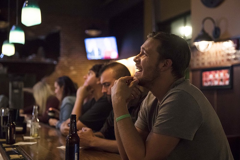 Roman Mitchell laughs as he watches the presidential debate between Democratic presidential nominee Hillary Clinton and Republican presidential nominee Donald Trump at Jefferson Social, Monday, Sept. 26, 2016, in downtown Cincinnati. 