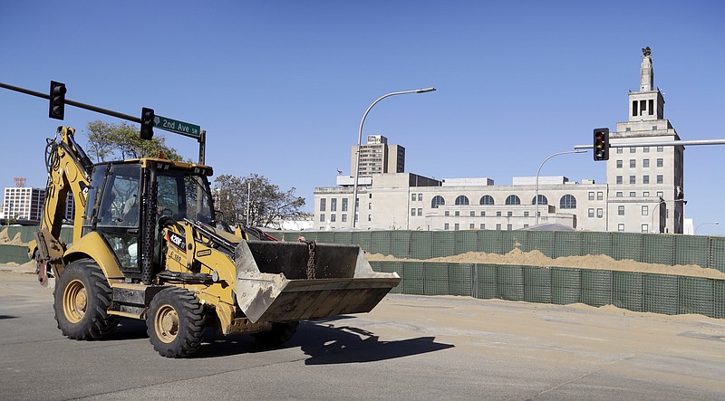 
              A worker drives a front end loader past a flood wall made of Hesco barriers on the bank of the Cedar River, Monday, Sept. 26, 2016, in Cedar Rapids, Iowa. Residents of Cedar Rapids are waiting anxiously as the quickly rising river threatens to inundate their city with devastating floodwaters. (AP Photo/Charlie Neibergall)
            