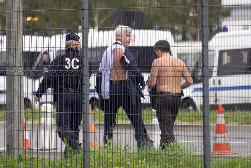 
              FILE - In this Monday, Oct. 5, 2015 file photo, Air France director of Human Resources Xavier Broseta, right, and Air France assistant director of long-haul flights Pierre Plissonnier, center, are protected by a police officer as they flee Air France headquarters at Roissy Airport, north of Paris, France, after scuffles with union activists. A group of former Air France workers is going on trial for allegedly taking part in violence that erupted during a union protest last year at the airline’s headquarters and left two executives fleeing over a fence with their shirts ripped off. (AP Photo/Jacques Brinon, File)
            