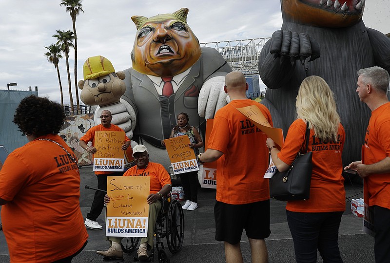 
              FILE - In this Sept. 21, 2016 file photo, Laborers' International Union of North America members and Culinary Union members walk by an inflatable figure depicting Donald Trump during a protest outside of the Trump International hotel, in Las Vegas. The unions were protesting what they say is an anti-union stance by the hotel. Union members are calling the public to boycott Republican presidential nominee Trump's businesses nationwide because he isn't negotiating a contract with the more than 500 eligible workers at his high-rise Las Vegas hotel. (AP Photo/John Locher, File)
            