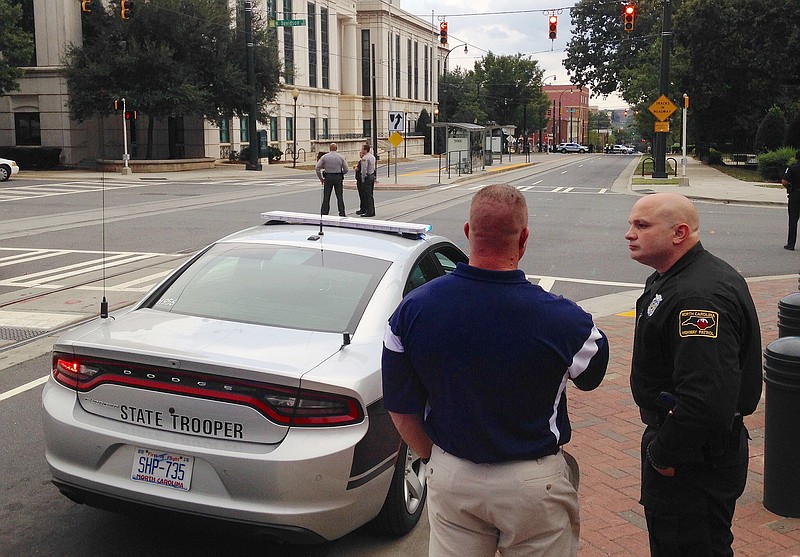 
              Law enforcement officers gather outside police headquarters in Charlotte, N.C., on Tuesday, Sept. 27, 2016, after a suspicious package was found inside the building. A city spokesman says the structure was evacuated and searched as a precaution following days of protests over the fatal police shooting of a black man. (AP Photo/Jay Reeves)
            