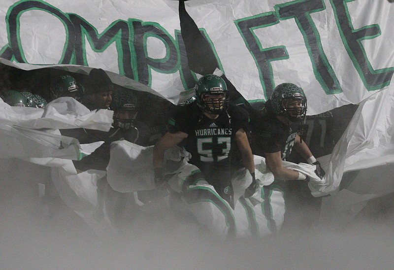 Members of the East Hamilton Hurricanes football team break through a banner prior to a home football game.