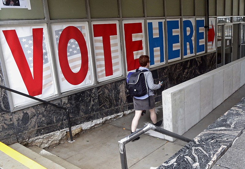 FILE - In this Sept. 23, 2016 file photo, a voter woman passes a large sign before voting in Minneapolis. More people are seeking or casting early ballots in the critical states of North Carolina and Florida than at this point in 2012, with Hillary Clinton the likely benefactor, as early voting shows signs of surging nationwide. (AP Photo/Jim Mone, File)