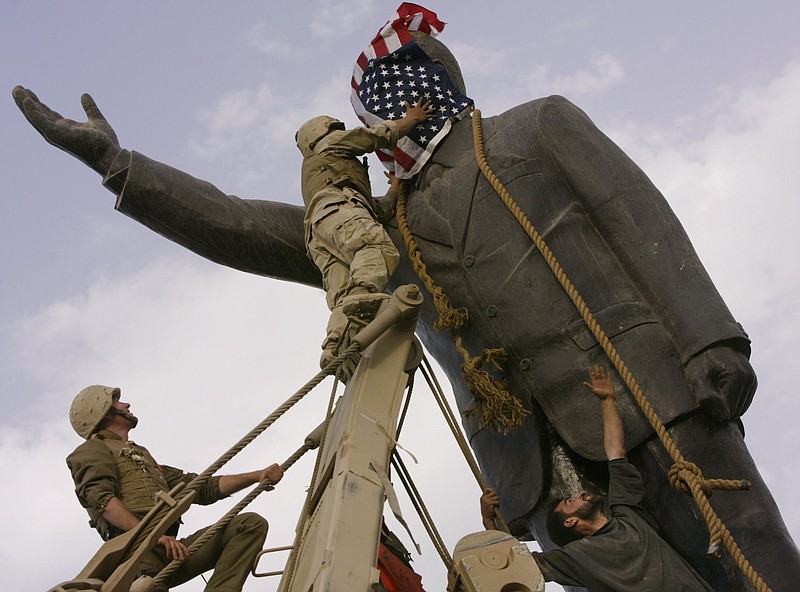 
              FILE - In this file photo taken Wednesday, April 9, 2003, an Iraqi man, bottom right, watches Cpl. Edward Chin of the 3rd Battalion, 4th Marines Regiment, cover the face of a statue of Saddam Hussein with an American flag before toppling the statue in downtown in Baghdad, Iraq. A bill passed by Congress allowing the families of 9/11 victims to sue the Saudi government has reinforced to some in the Arab world a long-held view that the U.S. only demands justice for its own victims of terrorism, despite decades of controversial U.S. interventions around the world. (AP Photo/Jerome Delay, File)
            