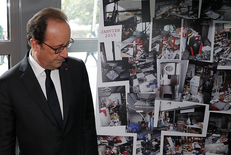 
              French President Francois Hollande walks past photographs of the devastated printing plant after the attack, as the plant reopens Thursday Sept. 29, 2016 in Dammartin-en-Goele, north of Paris. The plant is reopening for the first time since it was damaged during a deadly standoff between police and two brothers who gunned down cartoonists at Charlie Hebdo newspaper in Jan. 2015. (Philippe Wojazer, Pool photo via AP)
            