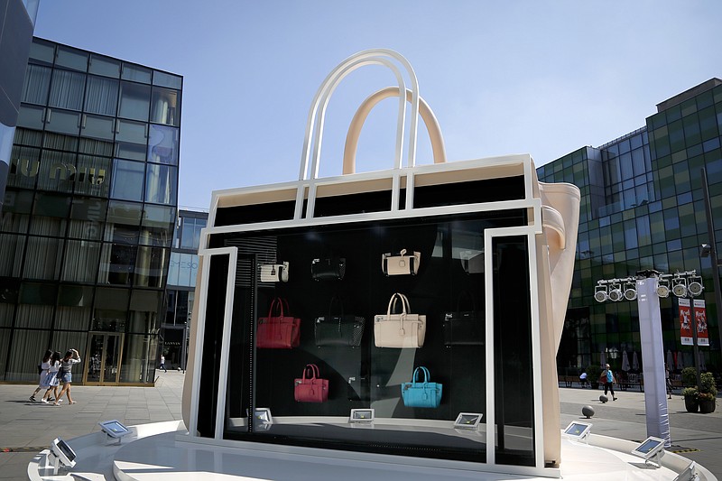 
              In this Sept. 5, 2016 photo, people walk by a giant handbag showcasing its different design on display at a up-scale shopping mall in Beijing. Chinese factories eked out a tiny expansion in activity for September as new orders picked up marginally, offering a glimmer of hope for the world's No. 2 economy, according to a private survey Friday, Sept. 30, 2016. (AP Photo/Andy Wong)
            