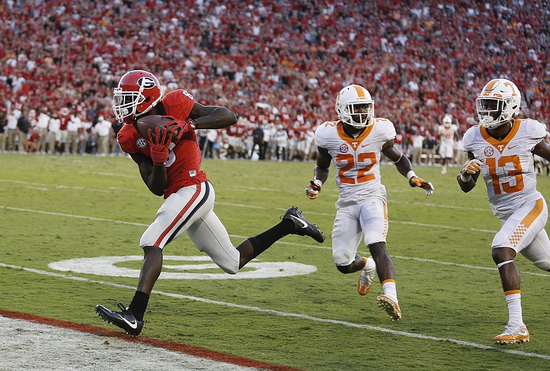 Georgia wide receiver Riley Ridley (8) runs away from Tennessee defensive backs Micah Abernathy (22) and  Malik Foreman (13) to score on a pass from quarterback Jacob Eason in the second half of an NCAA college football game Saturday, Oct. 1, 2016, in Athens, Ga. The touchdown briefly gave Georgia the lead but Tennessee scored on the game's last play to win 34-31. (AP Photo/John Bazemore)