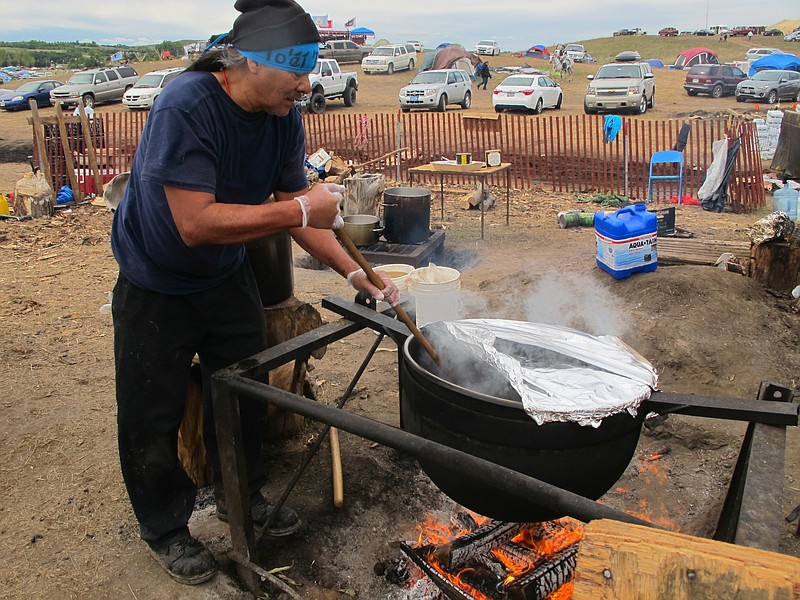 
              FILE - In this Sept. 9, 2016 file photo, Phil Daw Sr., of Albuquerque, New Mexico, helps cook beef stew to feed hundreds at an encampment near North Dakota's Standing Rock Sioux reservation. The sprawling encampment that’s a protest against the four-state Dakota Access oil pipeline has most everything it needs to be self-sustaining _ except a federal permit to be there. The camp near the confluence of the Missouri and Cannonball rivers in North Dakota is on U.S. Army Corps of Engineers land. (AP Photo/James MacPherson)
            