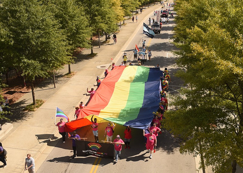 Approximately two dozen people march west on Riverside Drive with the Tennessee Valley Pride Organization flag midday Sunday in the Pride parade.
