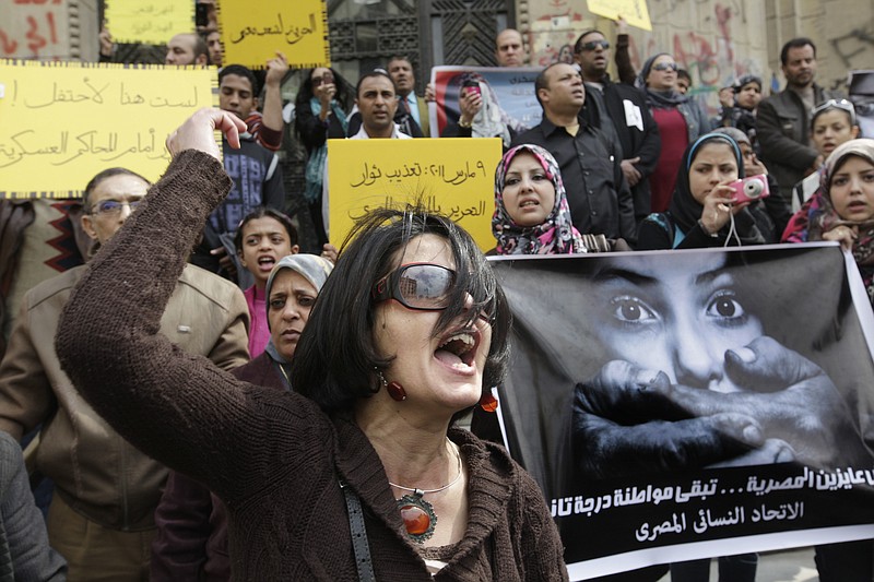 
              FILE - In this Friday, March 16, 2012, file photo, an Egyptian activist shouts anti-military Supreme Council slogans during a demonstration in front of Cairo's high court, Egypt. An independent Egyptian daily says the state’s top women’s advocacy group has filed a complaint with the chief prosecutor against a lawmaker who called for mandatory virginity tests for women seeking university admission. Arabic reads " March 9, 2011, protesters torture " and " We did not want the Egyptian woman to be a second-class citizen". (AP Photo/Amr Nabil)
            