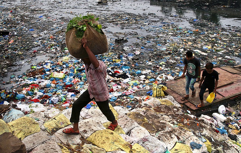 
              A man carries a sack of vegetables as he walks past a polluted canal littered with plastic bags and other garbage in Mumbai, India, Sunday, Oct. 2, 2016. India is scheduled to deposit the ratification instruments of the Paris Agreement on Climate Change with the United Nations on Sunday, the anniversary of Mahatma Gandhi's birth, who believed in a minimum carbon footprint. India accounts for about 4.5 percent of emissions. (AP Photo/Rafiq Maqbool)
            