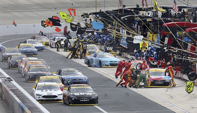 
              Early leaders, Kyle Busch, far right, Martin Truex Jr., front left, (78) and others make pit stops under caution during a NASCAR Sprint Cup Series auto race, Sunday, Oct. 2, 2016, at Dover International Speedway in Dover, Del. (AP Photo/Mel Evans)
            