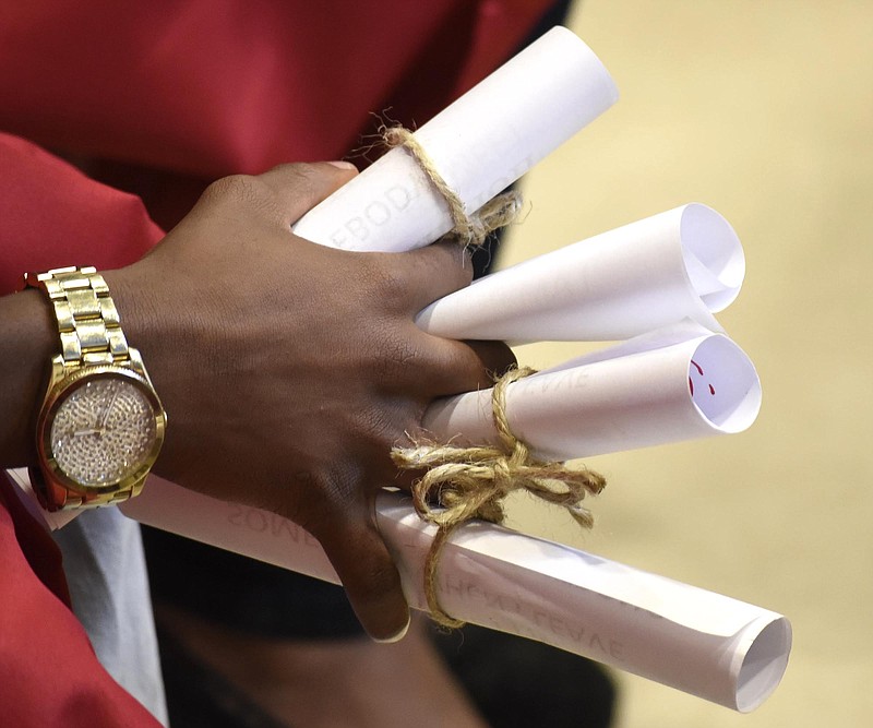 A Brainerd High School senior holds some of the many diploma that he and other seniors were presented by Orchard Knob Elementary students. BHS' 2016 graduating class walked through the halls of Orchard Knob Elementary in their caps and gowns, as a representation of the "vision" for where the elementary students will one day be.