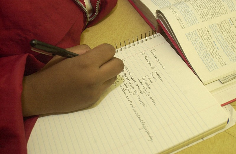 A Tyner Academy student takes notes on a discussion in history class.