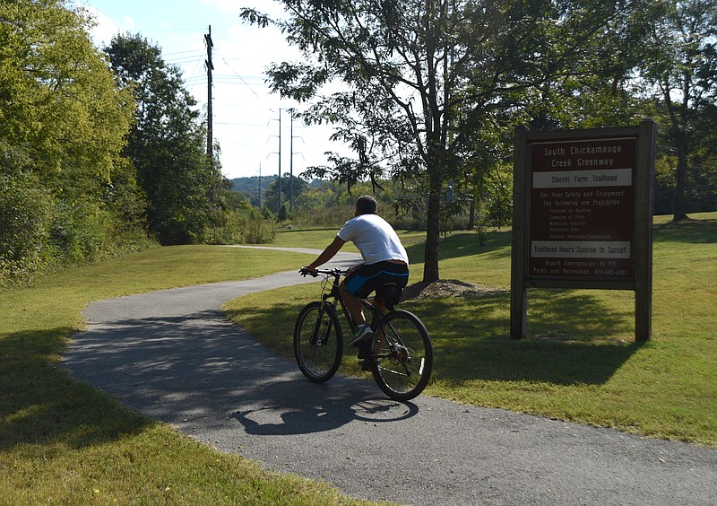 A cyclists rides past the sign for the Sterchi Farm trailhead of the South Chickamauga Creek Greenway Tuesday, Oct. 4, 2016.