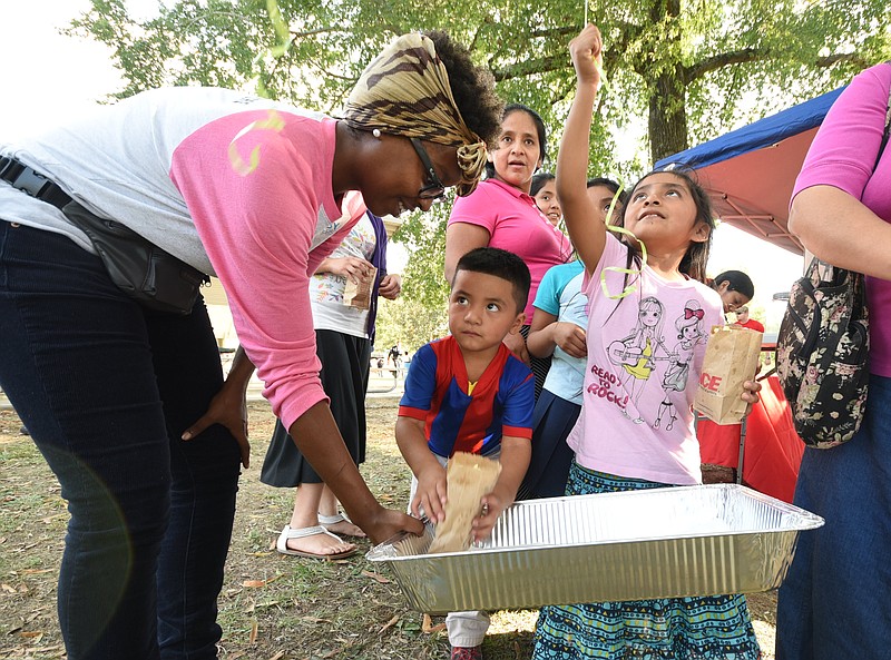 Eleyda Tomas, right, 6, watches her balloon fly as Chattanooga Baby University volunteer Lasha-Rockymore, left, offers popcorn to Roldy Tomas, 4, on  Tuesday at the National Night Out event in East Lake Park. Vilma Simon, back center, looks on.