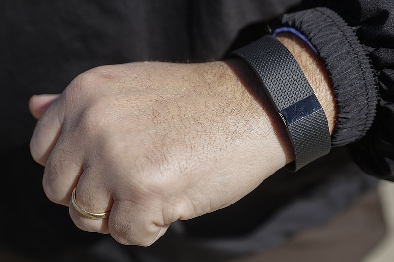 
              FILE - In this Monday, Feb. 29, 2016, file photo, Brett Broviak, a manager of respiratory and sleep services at IU Health North Hospital, shows off his Fitbit fitness tracker for the camera on the hospital's campus in Carmel, Ind. Wearing a stylish fitness tracker may help you keep tabs on things like how many steps you take, but the devices themselves _ even with the lure of a cash reward _ probably won’t improve your health, according to the biggest study yet done on the trendy technology. (AP Photo/AJ Mast, File)
            