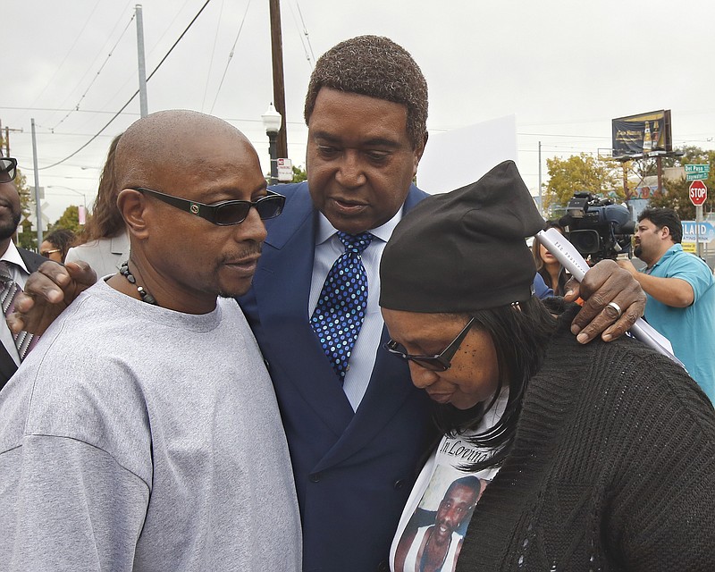 Attorney John Burris, center, comforts Robert and Deborah Mann, family members of Joseph Mann, who was killed by Sacramento Police in July, after a news conference Monday, Oct. 3, 2016, in Sacramento, Calif. The Mann family is demanding that the officers involved in shooting of Joseph Mann, 50, be charged with murder and that the U.S. Department of Justice open a civil rights investigation of the Sacramento Police Department.