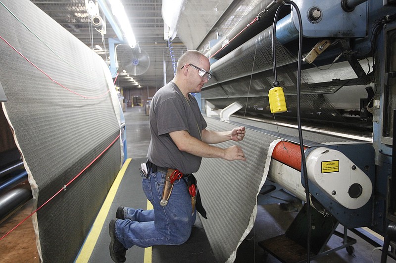 Staff file photo by Doug Strickland Worker Mathew Ferney works on a tufting machine at a Beaulieu of America factory in Dalton, Ga.