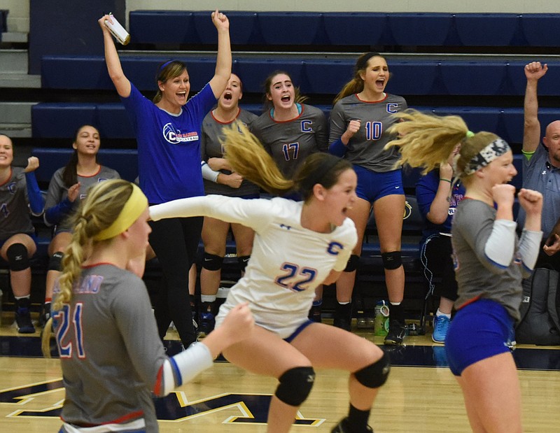 Cleveland volleyball coach Trish Flowers, top left, raises her arms in victory as her team erupts after defeating  Ooltewah for the District 5-AAA volleyball championship at Walker Valley.