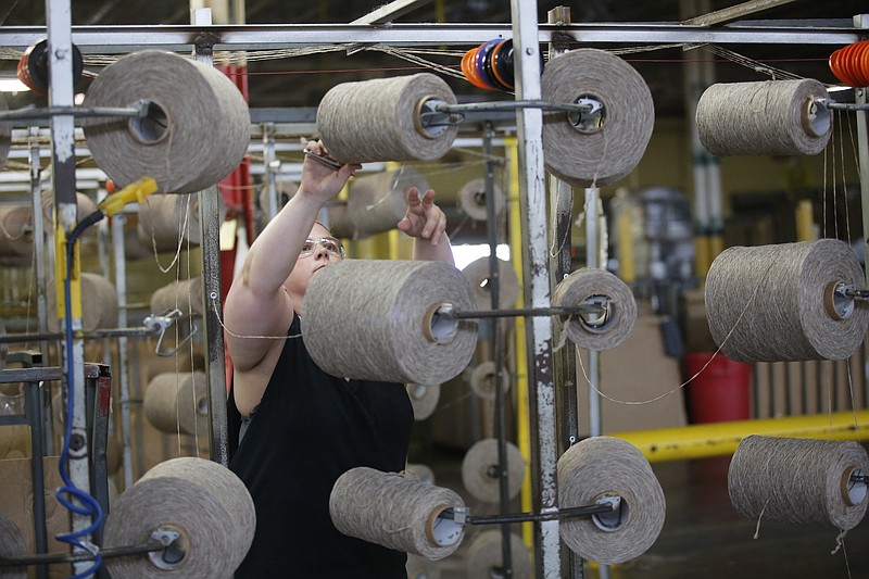 Worker Christy Anderson works on a machine used to roll yarn onto large spools Tuesday, June 17, 2014, at a Beaulieu of America factory in Dalton, Ga.